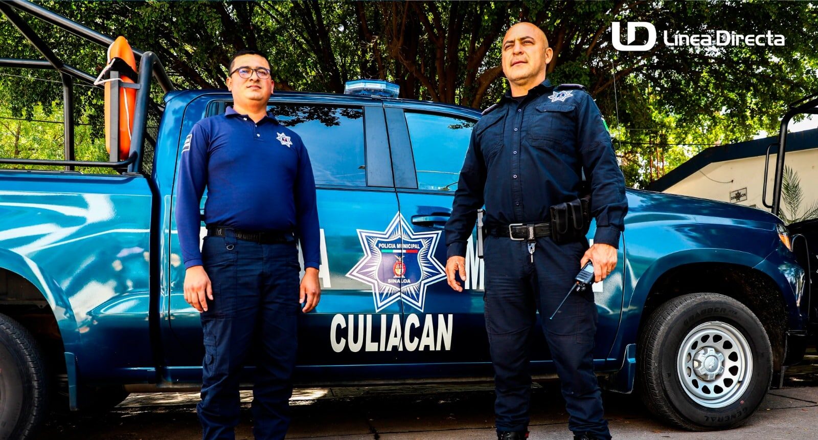 Dos policías de Culiacán frente a una patrulla de la Municipal