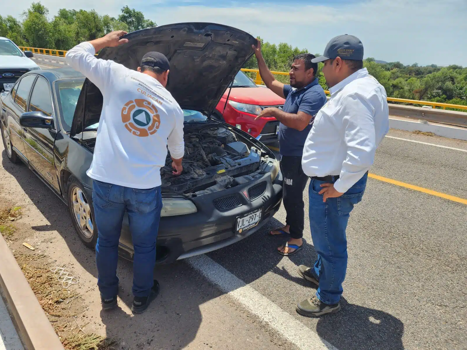 Protección civil ayudando a persona con automóvil dañado.