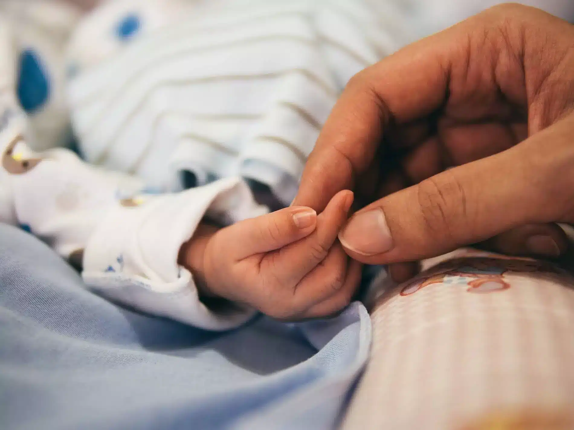 Mano de madre sostiene la mano de bebé hospitalizado