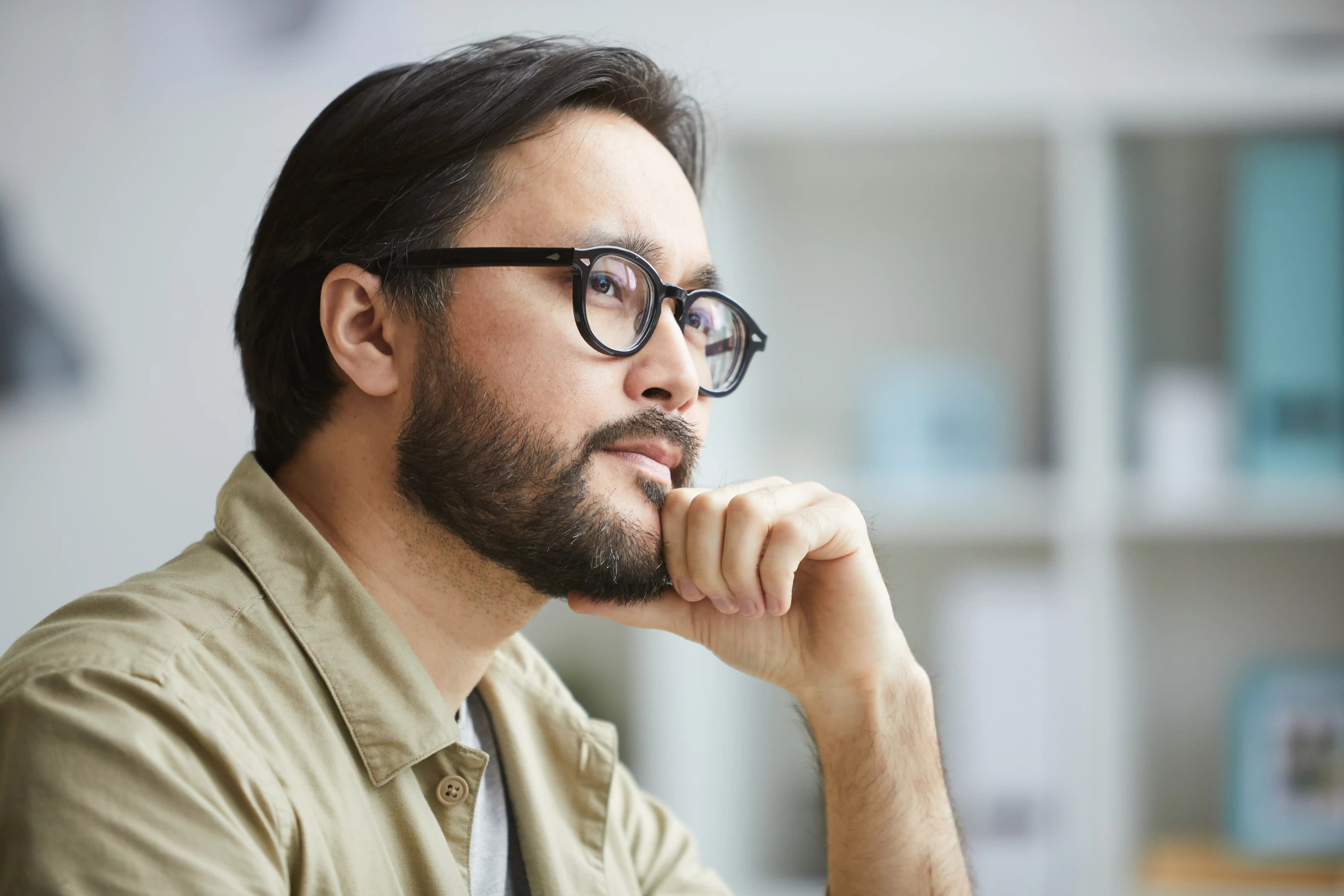 Hombre con gafas pensando profundamente en una oficina