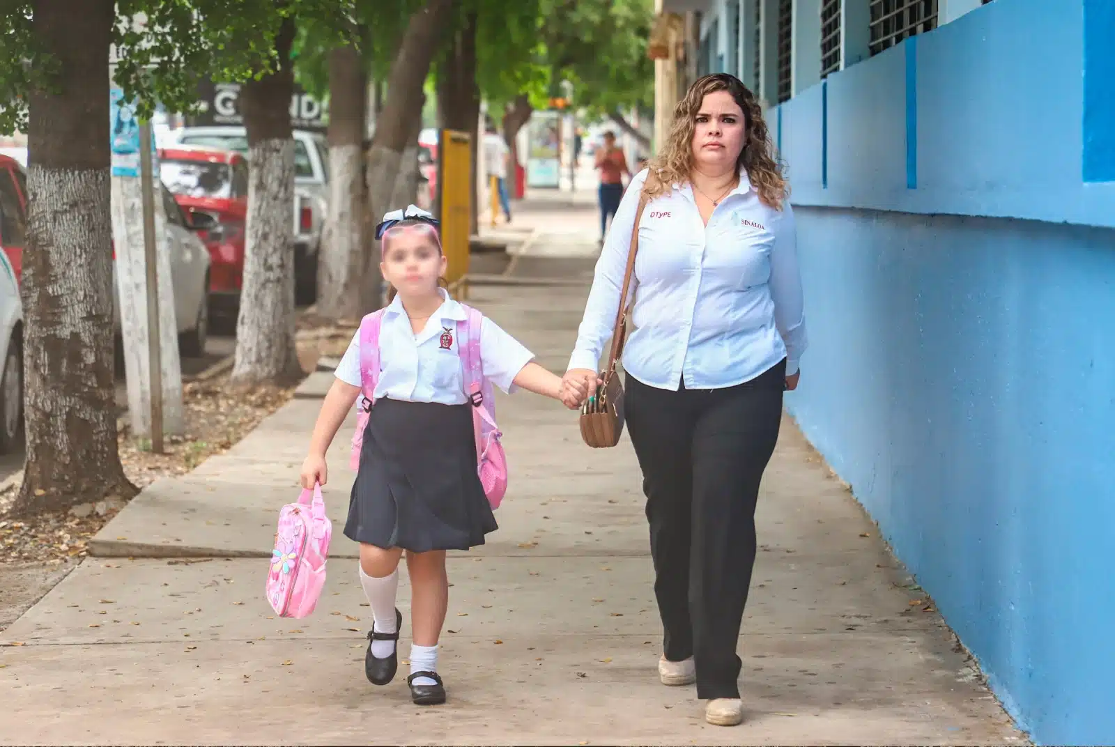 Madre lleva a hija a escuela primaria