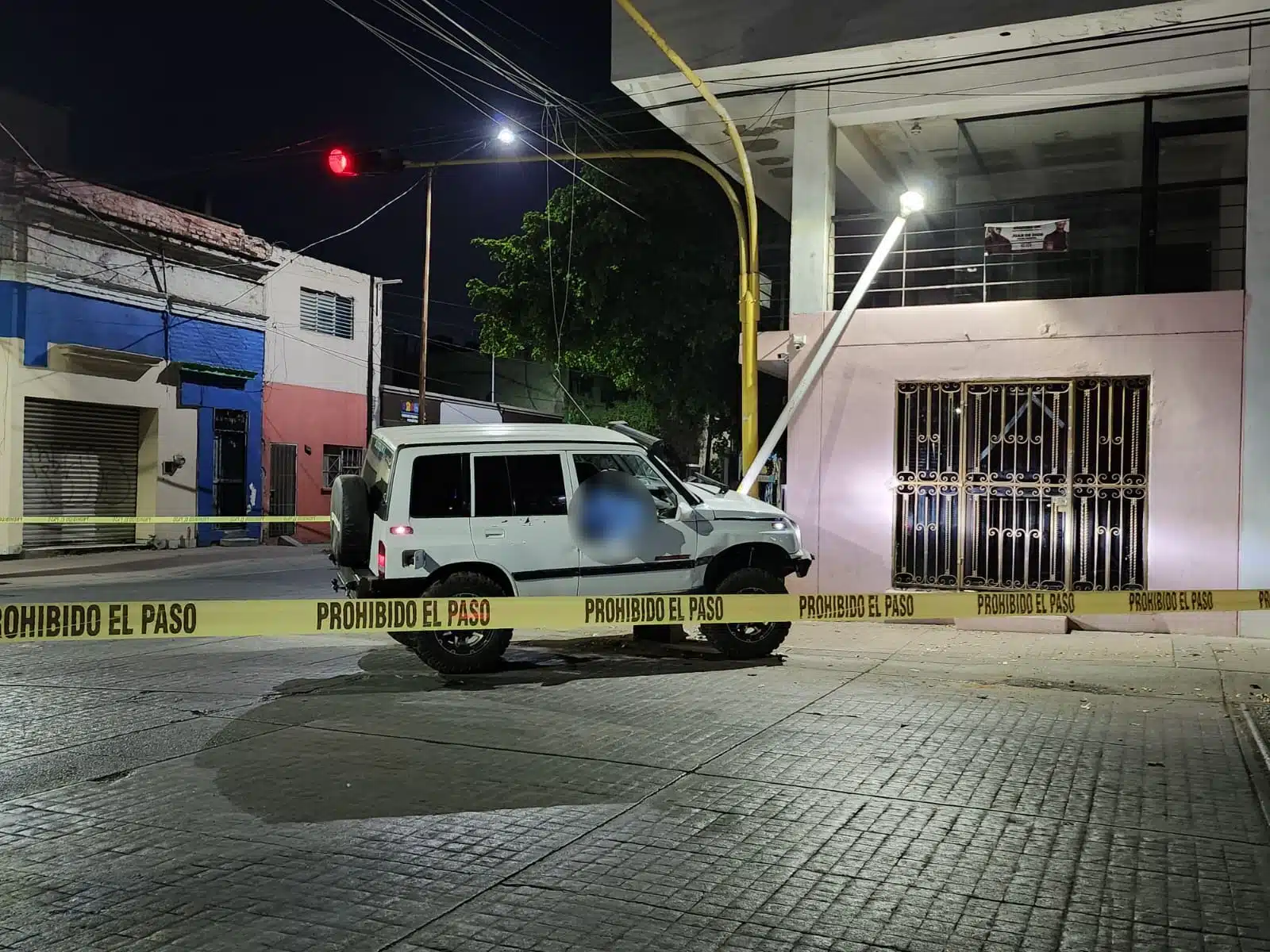 Cinta amarilla delimitando el área donde está una camioneta que manejaba un hombre que murió tras un presunto infarto y chocar contra una luminaria en Culiacán