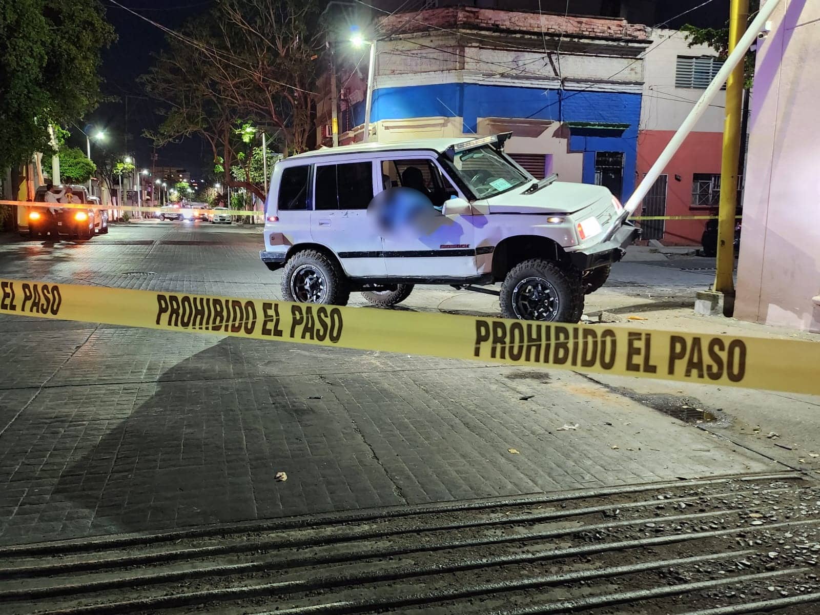 Cinta amarilla delimitando el área donde está una camioneta que manejaba un hombre que murió tras un presunto infarto y chocar contra una luminaria en Culiacán