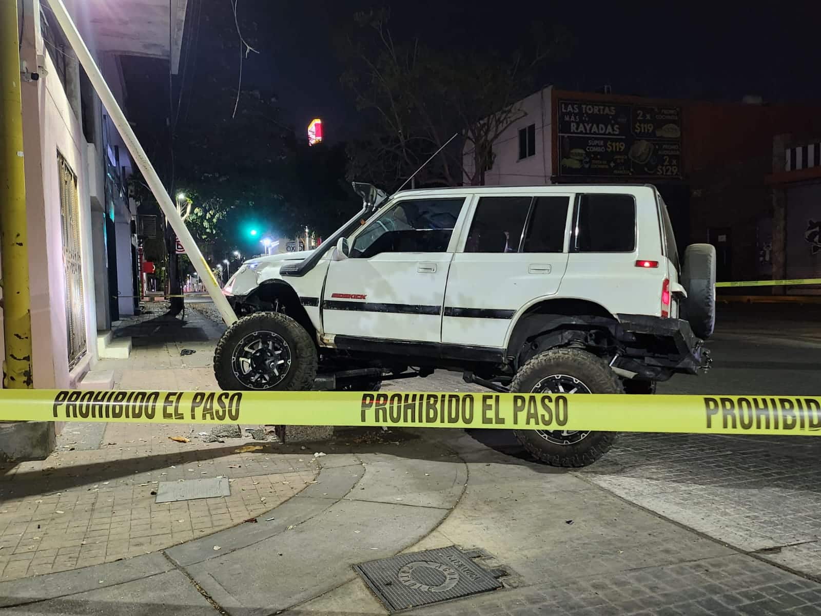 Cinta amarilla delimitando el área donde está una camioneta que manejaba un hombre que murió tras un presunto infarto y chocar contra una luminaria en Culiacán