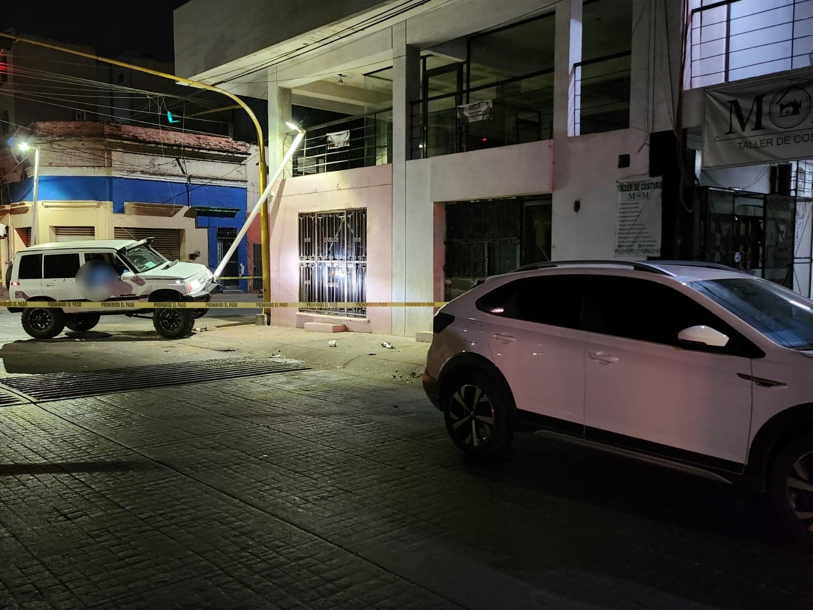 Cinta amarilla delimitando el área donde está una camioneta que manejaba un hombre que murió tras un presunto infarto y chocar contra una luminaria en Culiacán