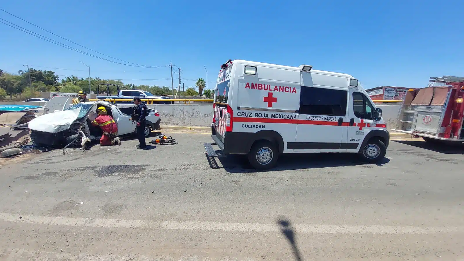 Camioneta destrozada de un lado tras un accidente tipo choque en la que viajaba Ángel y una ambulancia de la Cruz Roja en la carretera sobre el libramiento Benito Juárez "La Costerita" en Culiacán