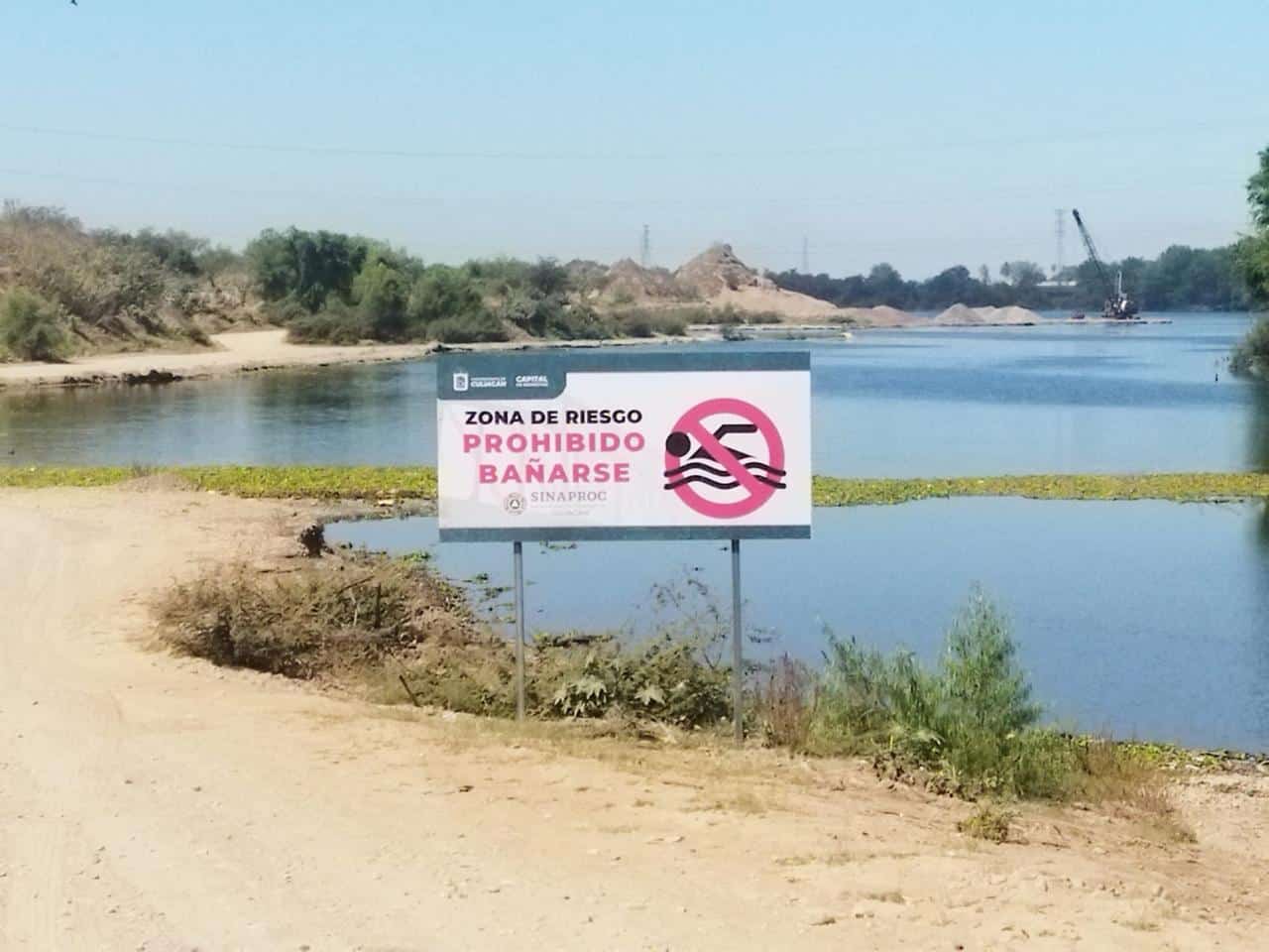 Rótulo anunciando zona de riesgo (prohibido bañarse) en el área de un río en Culiacán