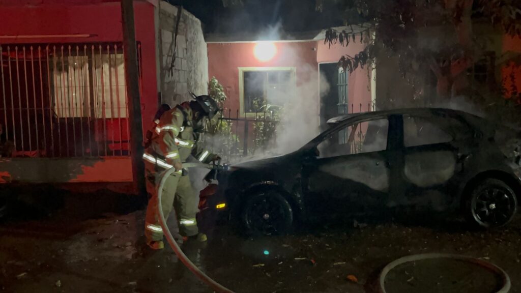 Bombero rocía agua sobre el vehículo incendiado