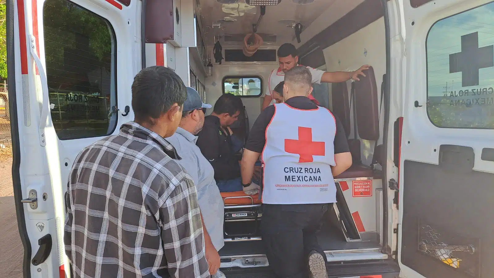 Ambulancia y elementos de la Cruz Roja atendiendo a un empleado que le picaron las abejas en una bodega de granos ubicada por la carretera Guamúchil-Angostura