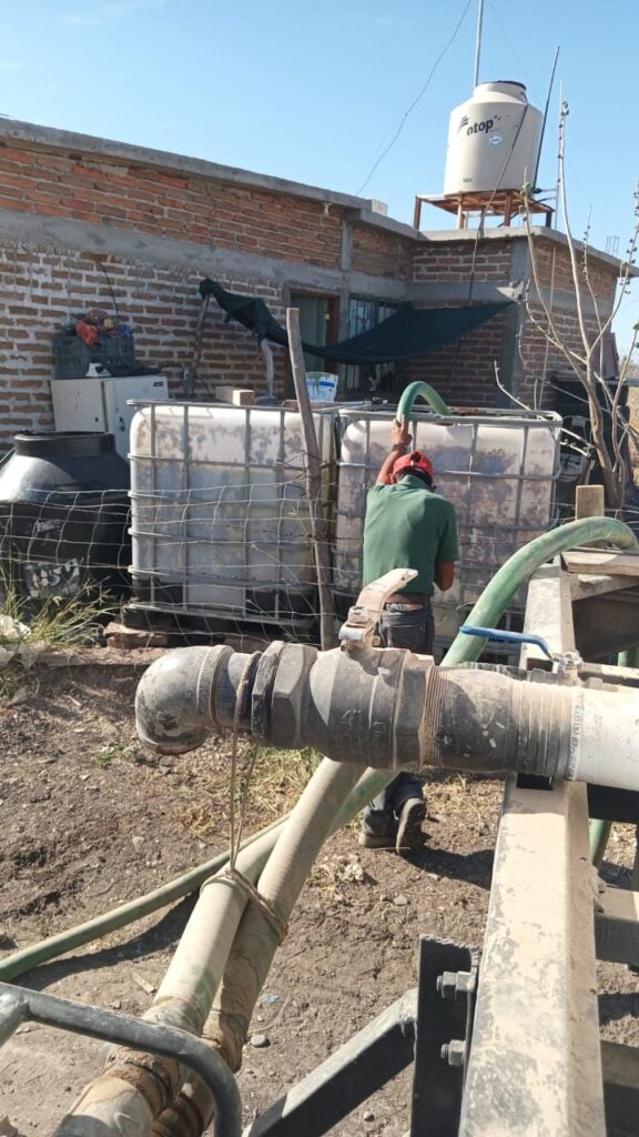 Una persona llenando de agua un tambo por la sequía en El Fuerte