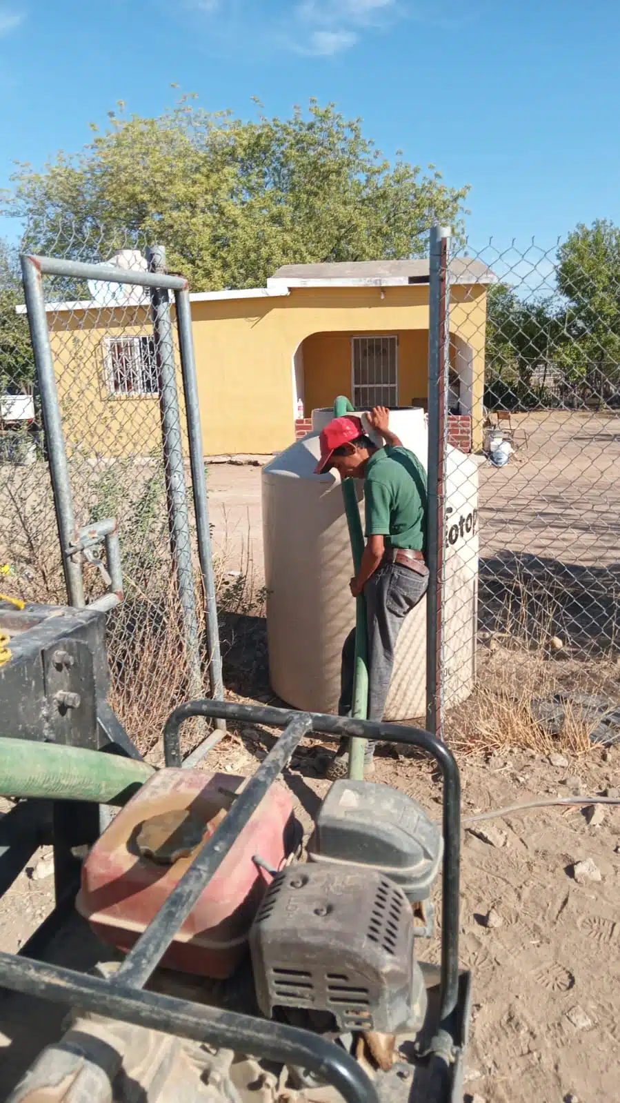 Una persona llenando de agua un tinaco por la sequía en El Fuerte