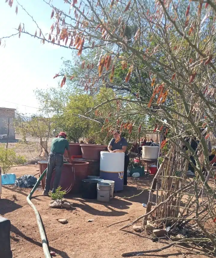 Una persona llenando de agua tambos por la sequía en El Fuerte