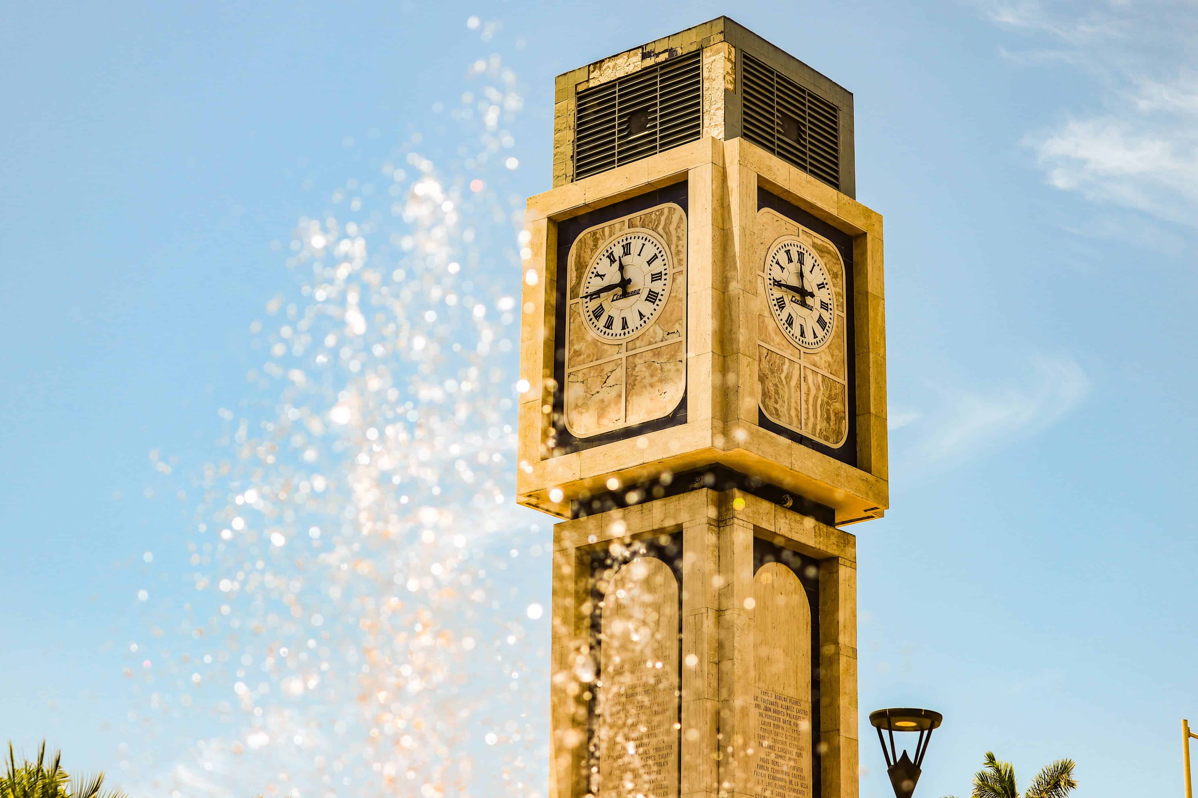 Fuente de agua durante día caluroso en plaza con torre de reloj en la ciudad de Culiacán