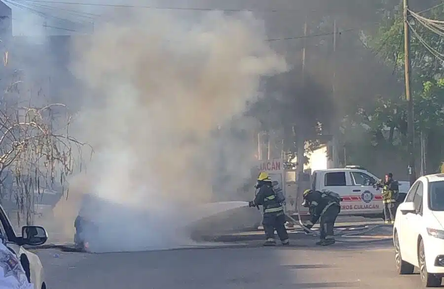 Bomberos sofocando el incendio que arrasó con el vehículo
