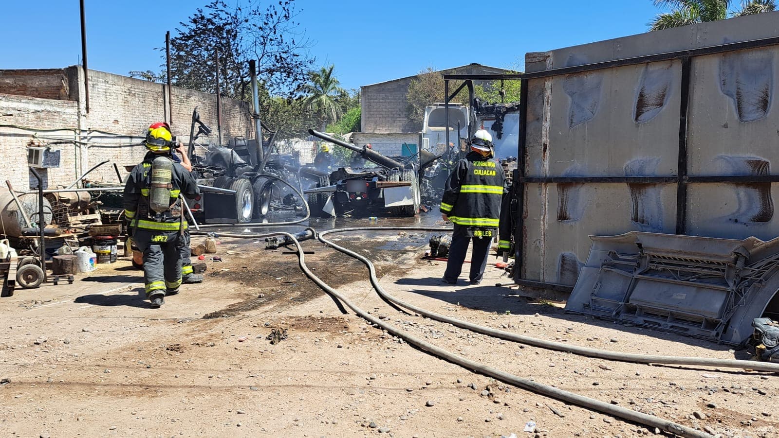 Elementos de bomberos en el lugar donde se incendiaron tres tractocamiones en Culiacán