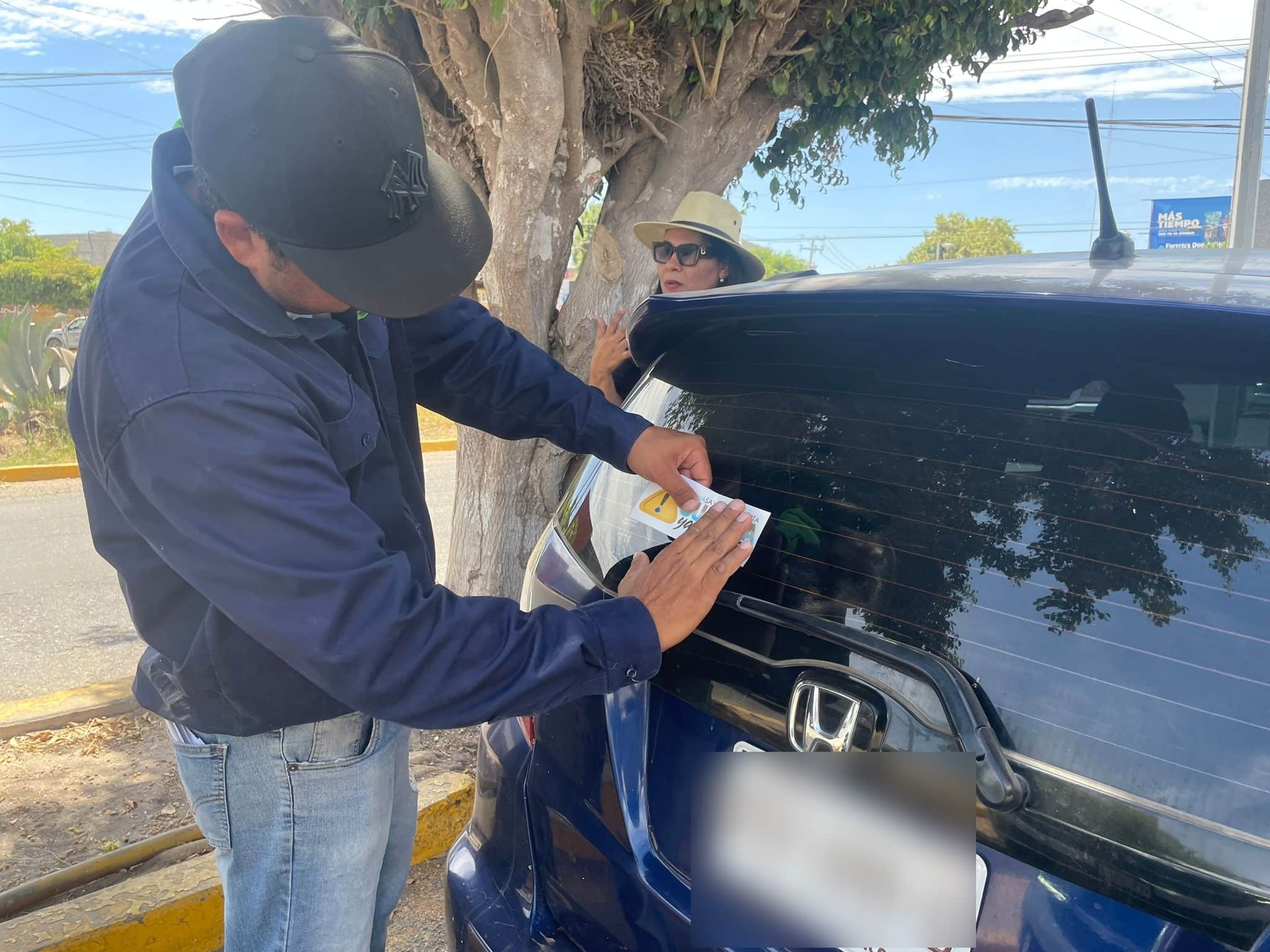 Personal de la Jumapag poniendo calcomanías en los carros en Guasave