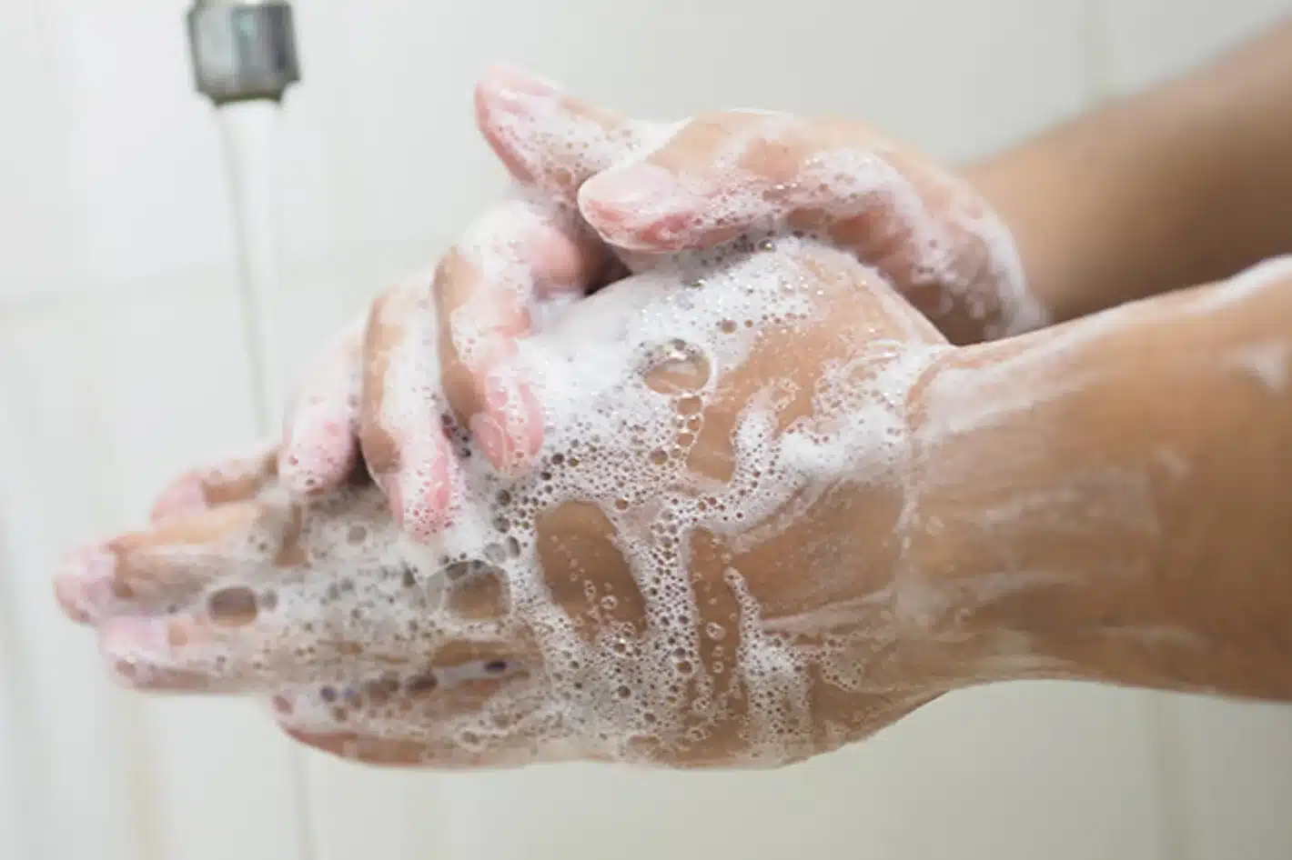 Una persona se frota las manos con agua y jabón