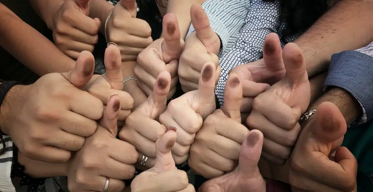 Manos de personas con pulgar pintado por votar