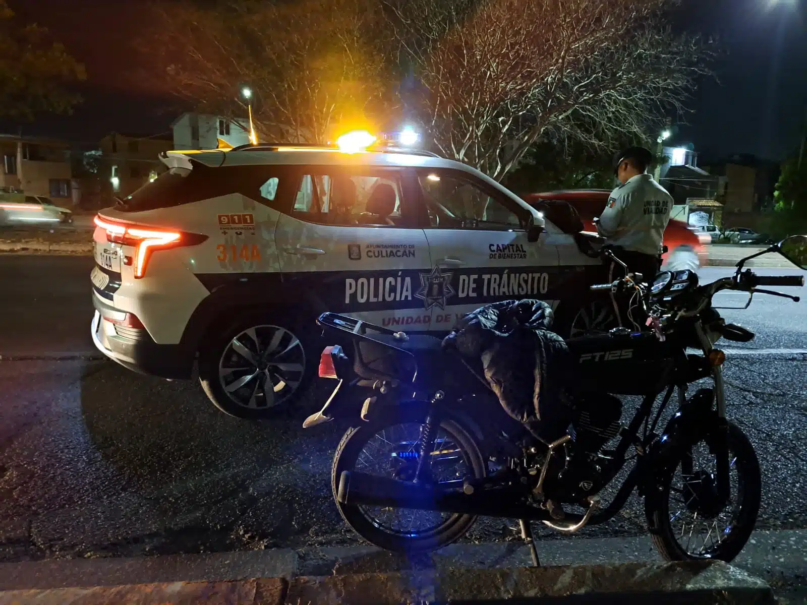 Patrulla y elemento de la Policía de Tránsito de Culiacán junto a una motocicleta en el lugar del accidente