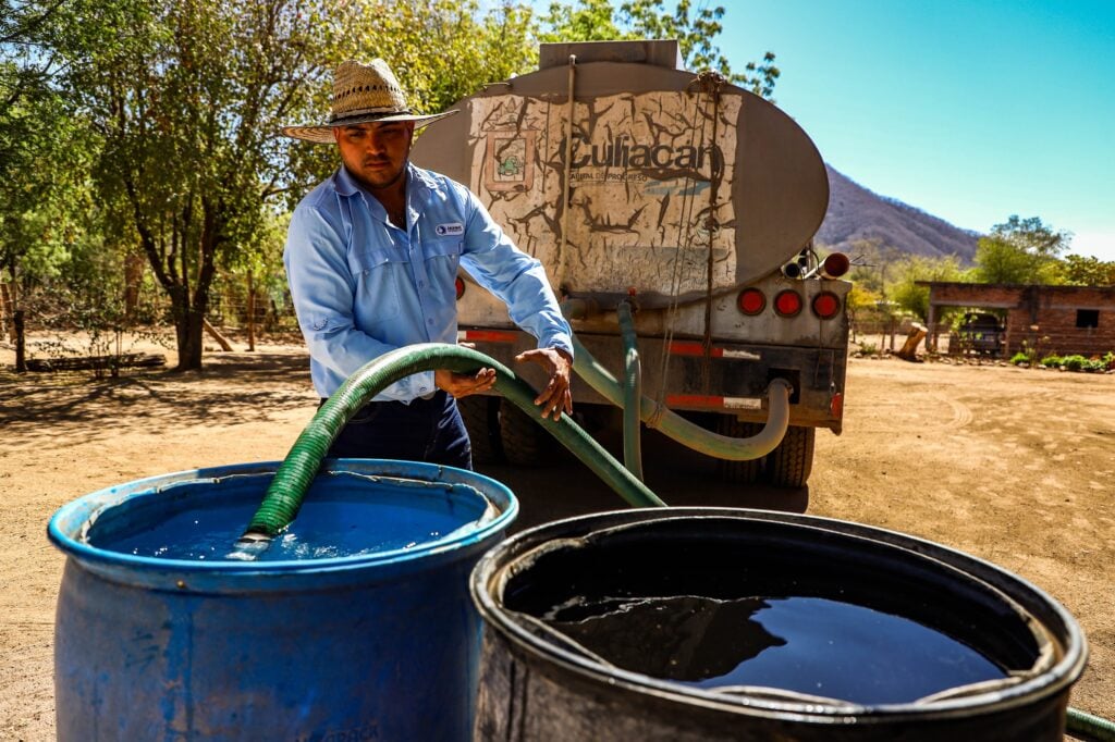 Hombre de Culiacán vaciando agua a un tambo 