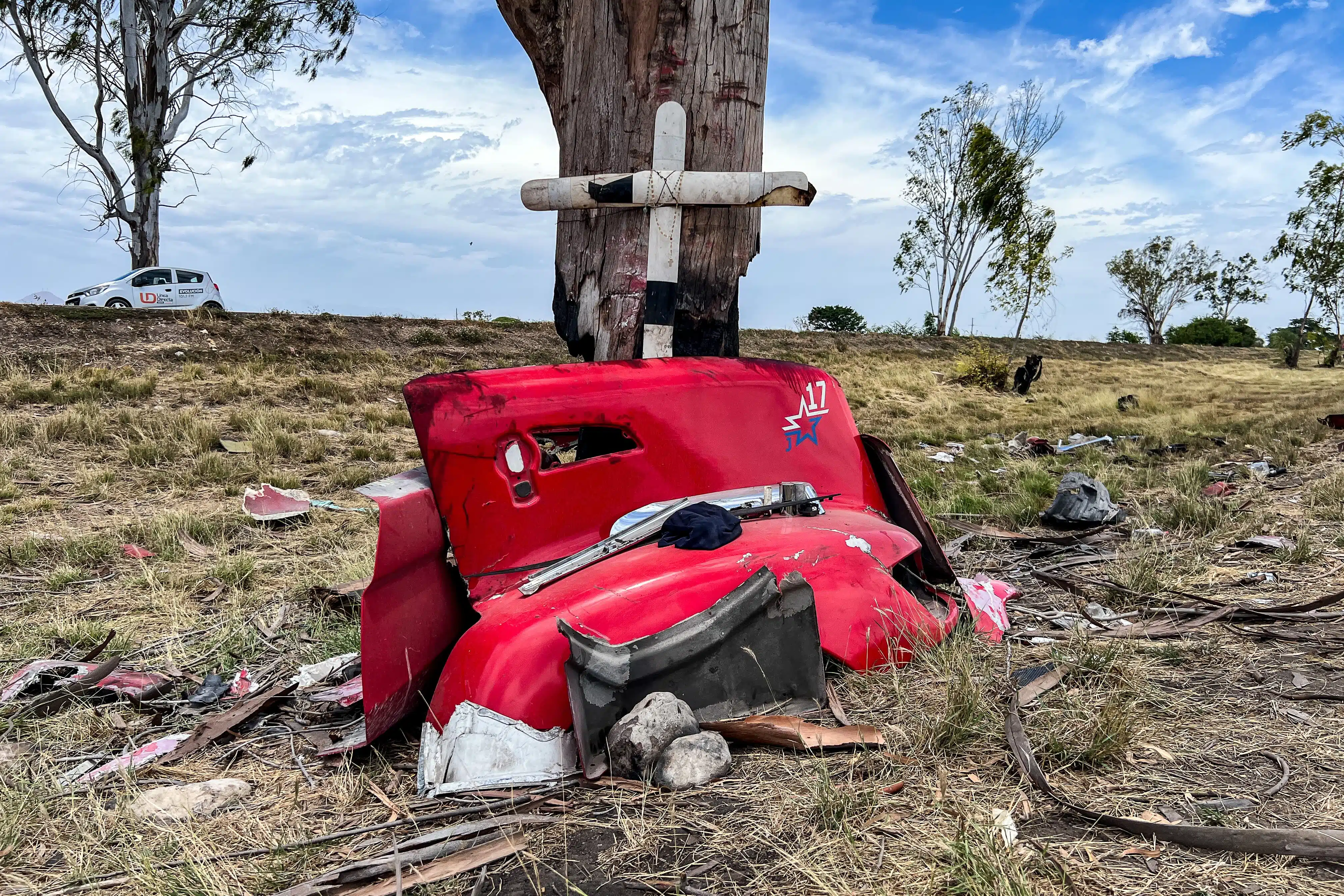 Una cruz en un árbol y restos de un tráiler color rojo en el lugar del accidente por la maxipista Culiacán-Mazatlán