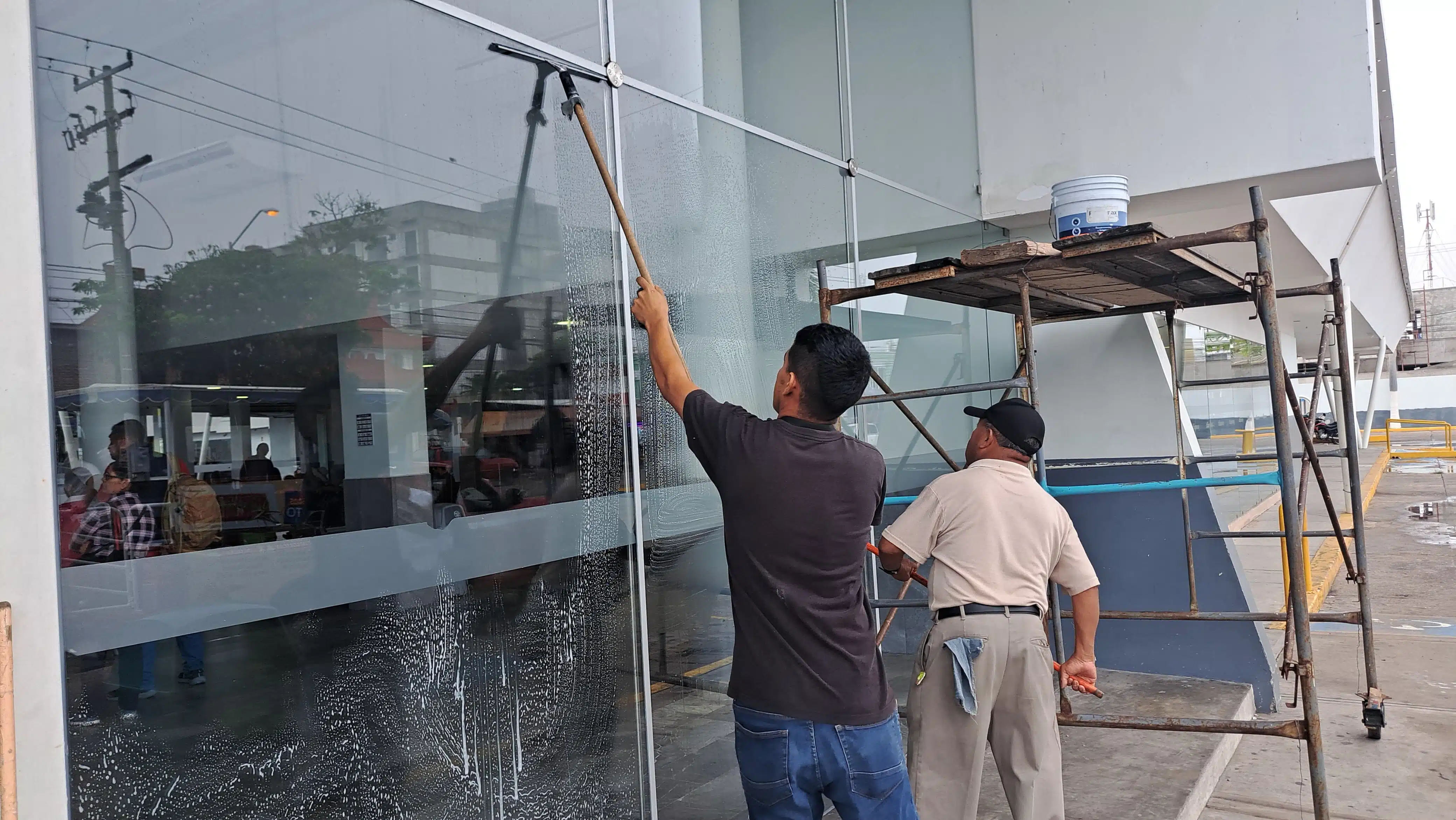 2 personas limpiando los cristales de la central de autobuses de Mazatlán