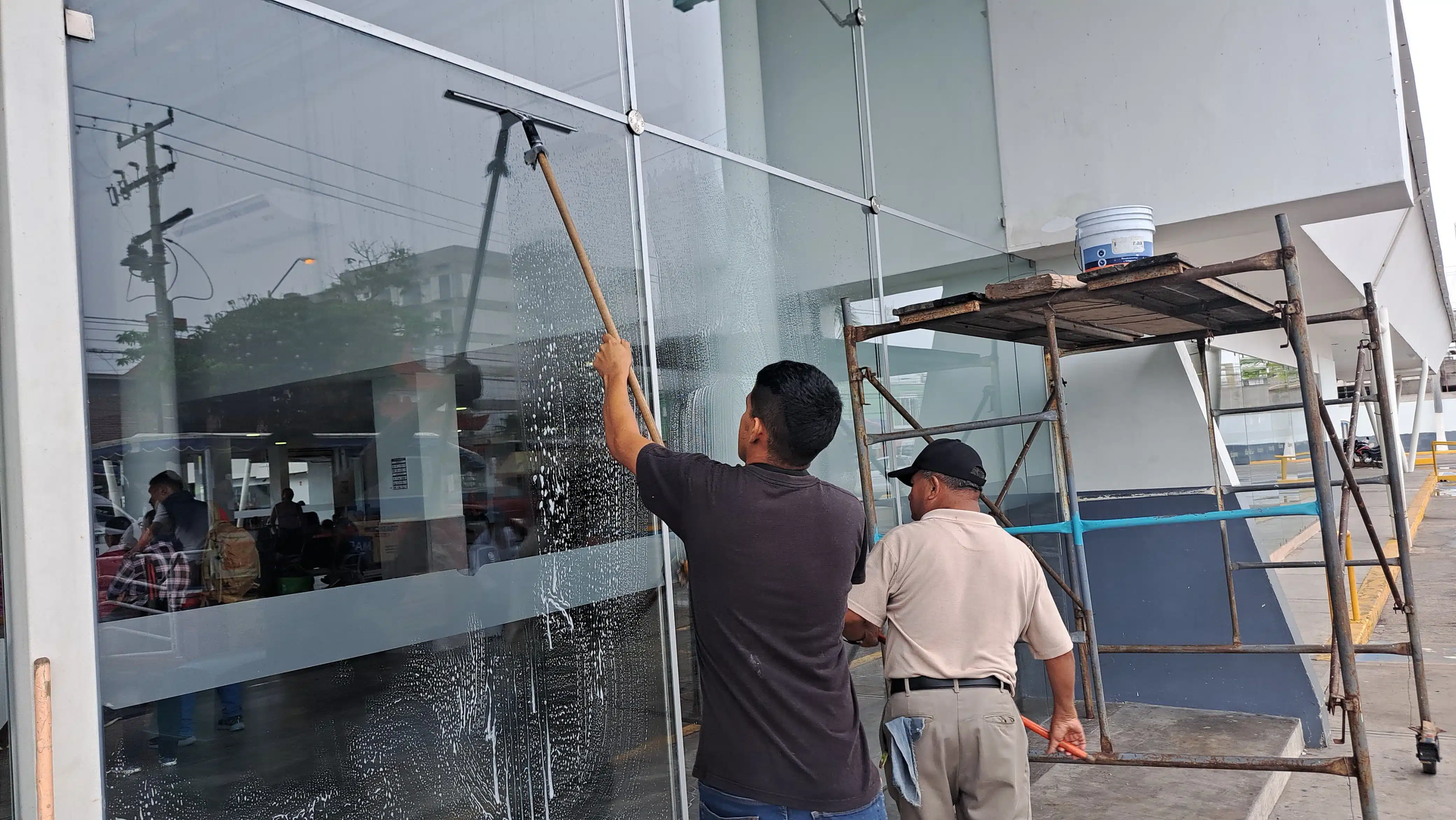 2 personas limpiando los cristales de la central de autobuses de Mazatlán