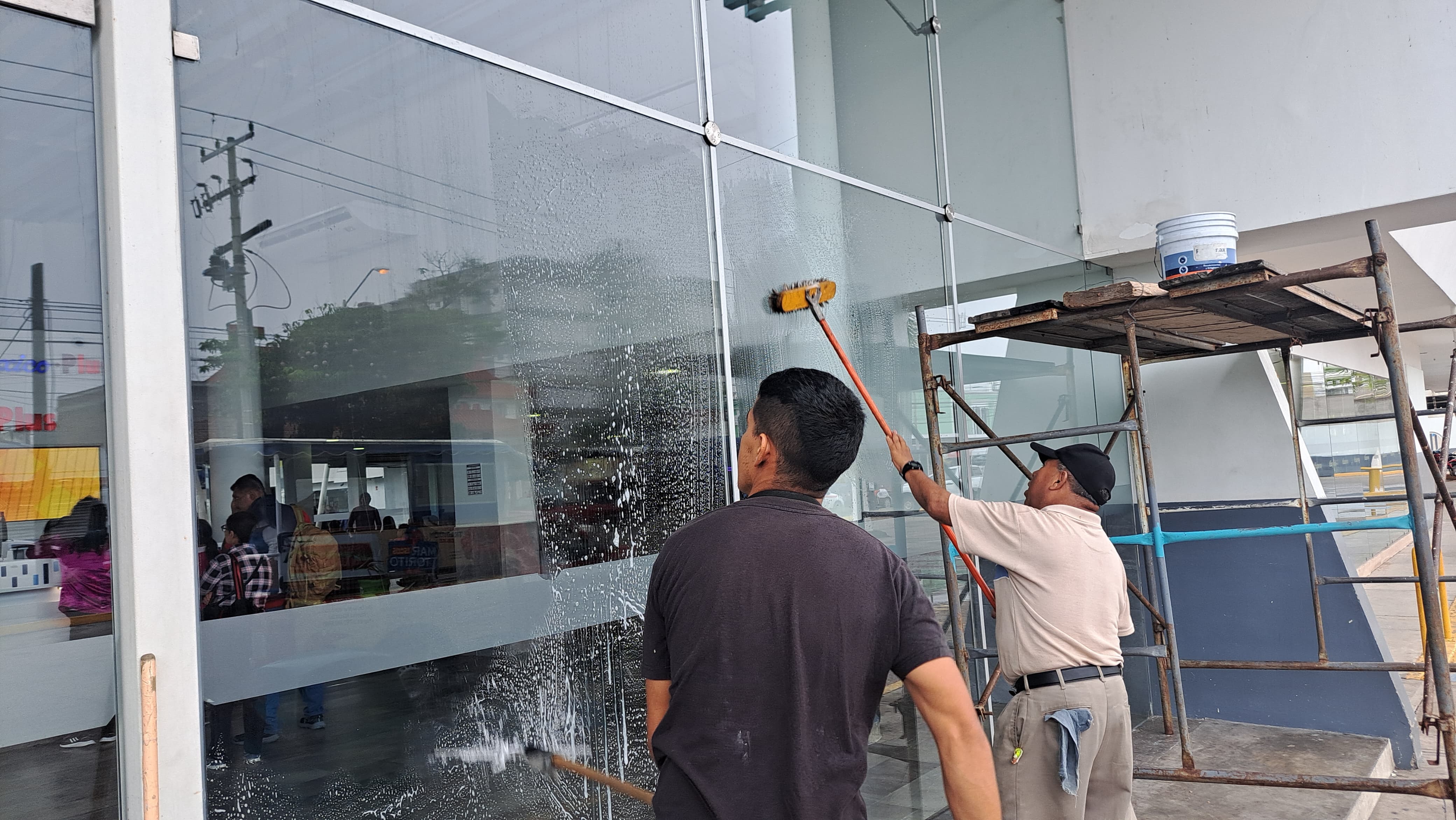 2 personas limpiando los cristales de la central de autobuses de Mazatlán
