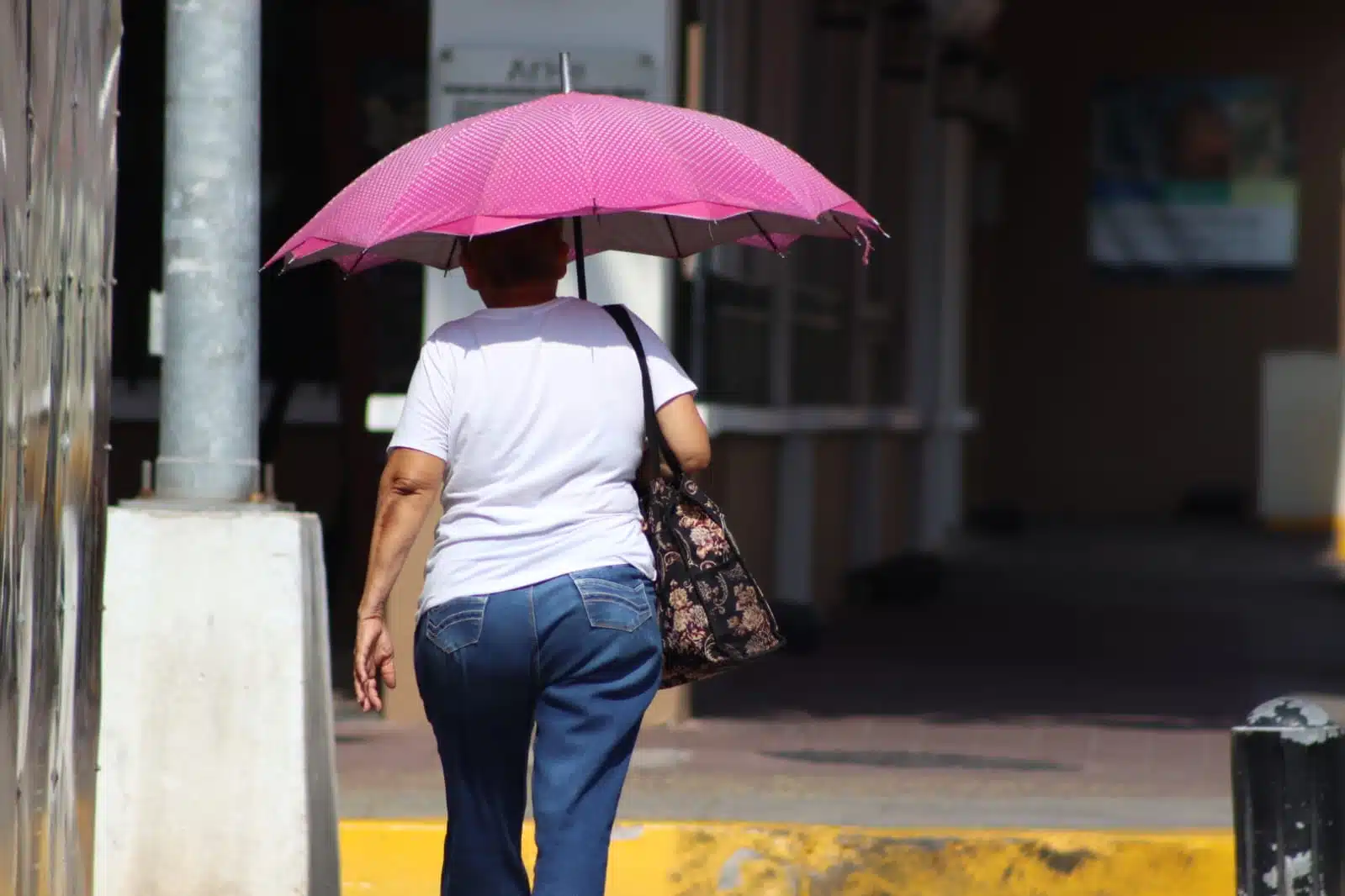 Mujer caminando por las calles de Mazatlán usando una sombrilla