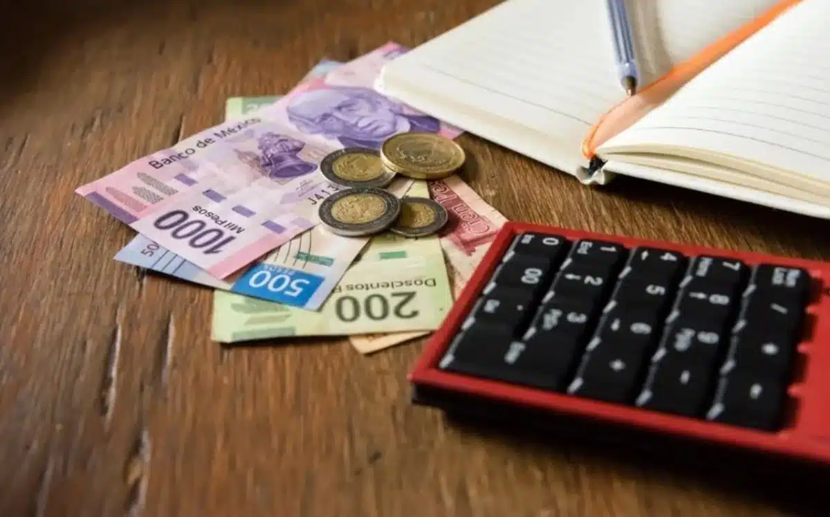 Billetes y monedas junto a una calculadora y una libreta