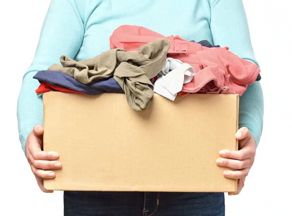 Una persona sosteniendo un caja con ropa para donarla