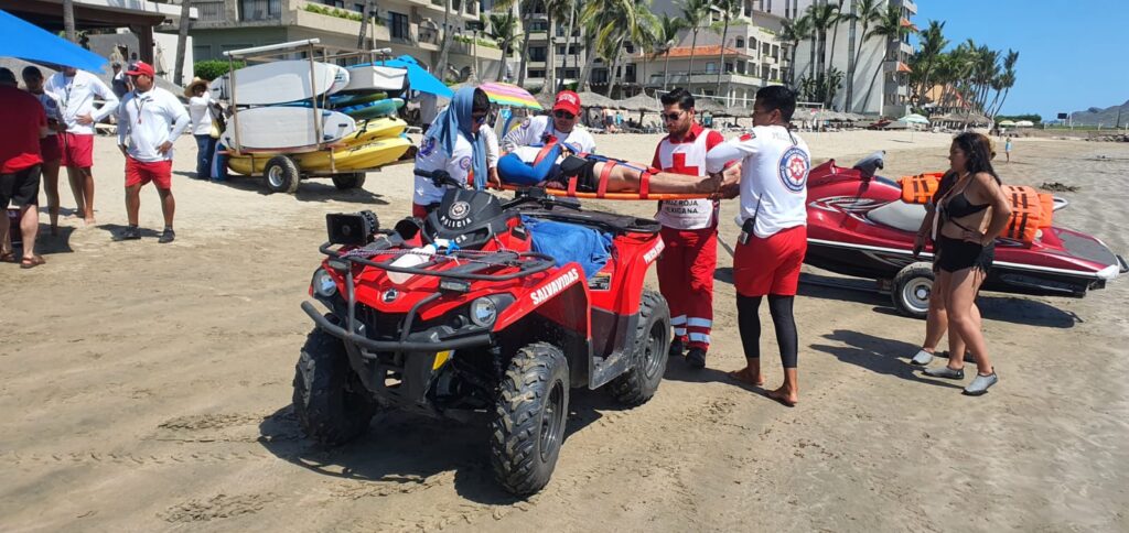 Elementos del escuadrón acuático y de la Cruz Roja de Mazatlán en la playa atendiendo a un joven