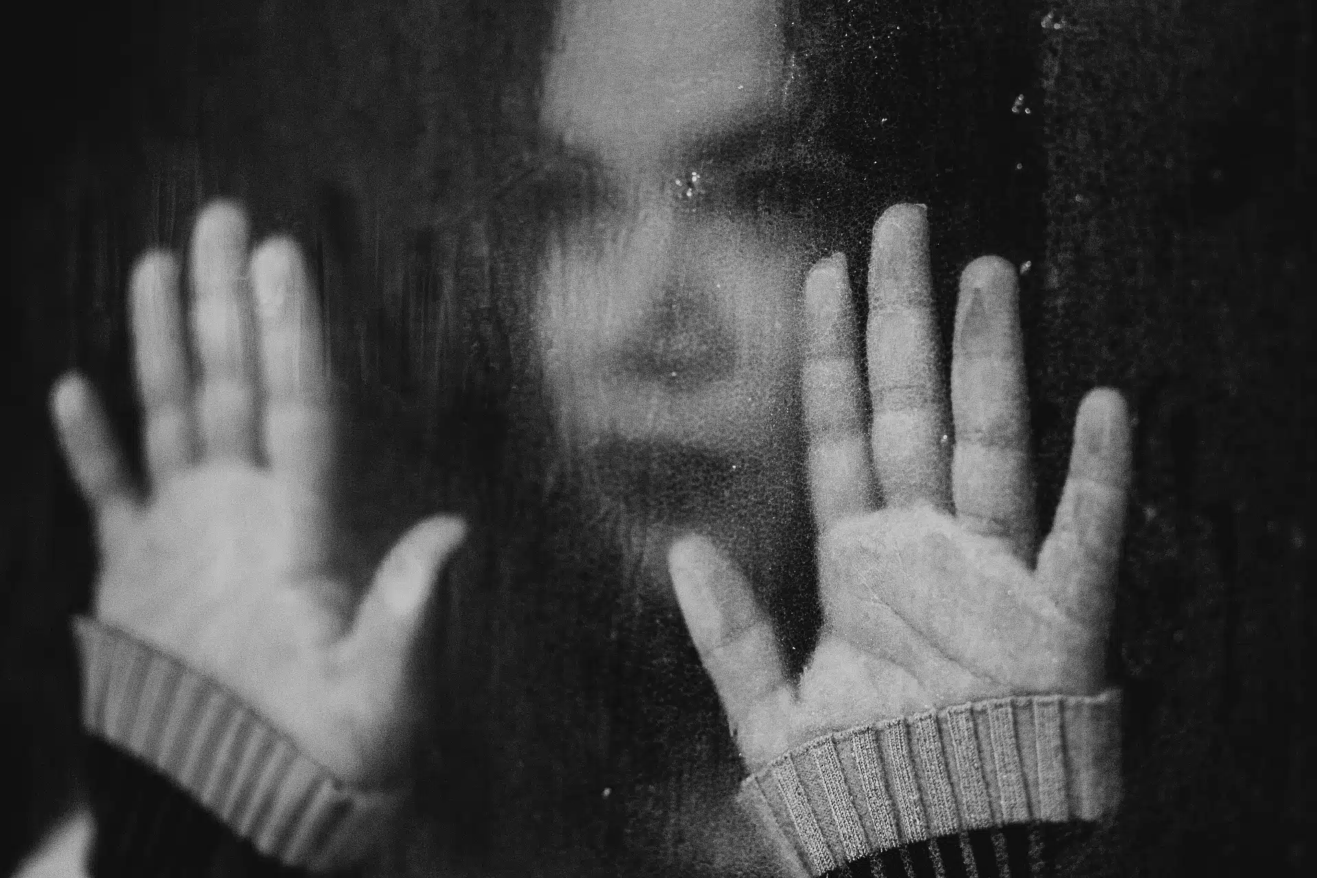 Imagen difusa de una mujer recargando sus manos sobre una ventana