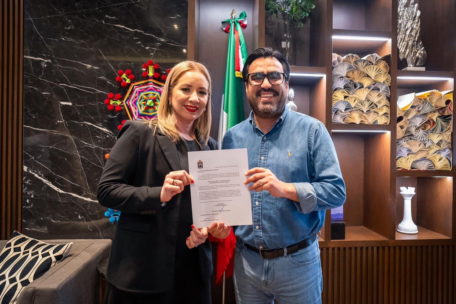 Juan de Dios Gámez Mendívil, presidente municipal de Culiacán, junto a María del Carmen Morales Donada, con una hoja en la que dice que es la nueva secretaria de Obras Públicas y Servicios Públicos