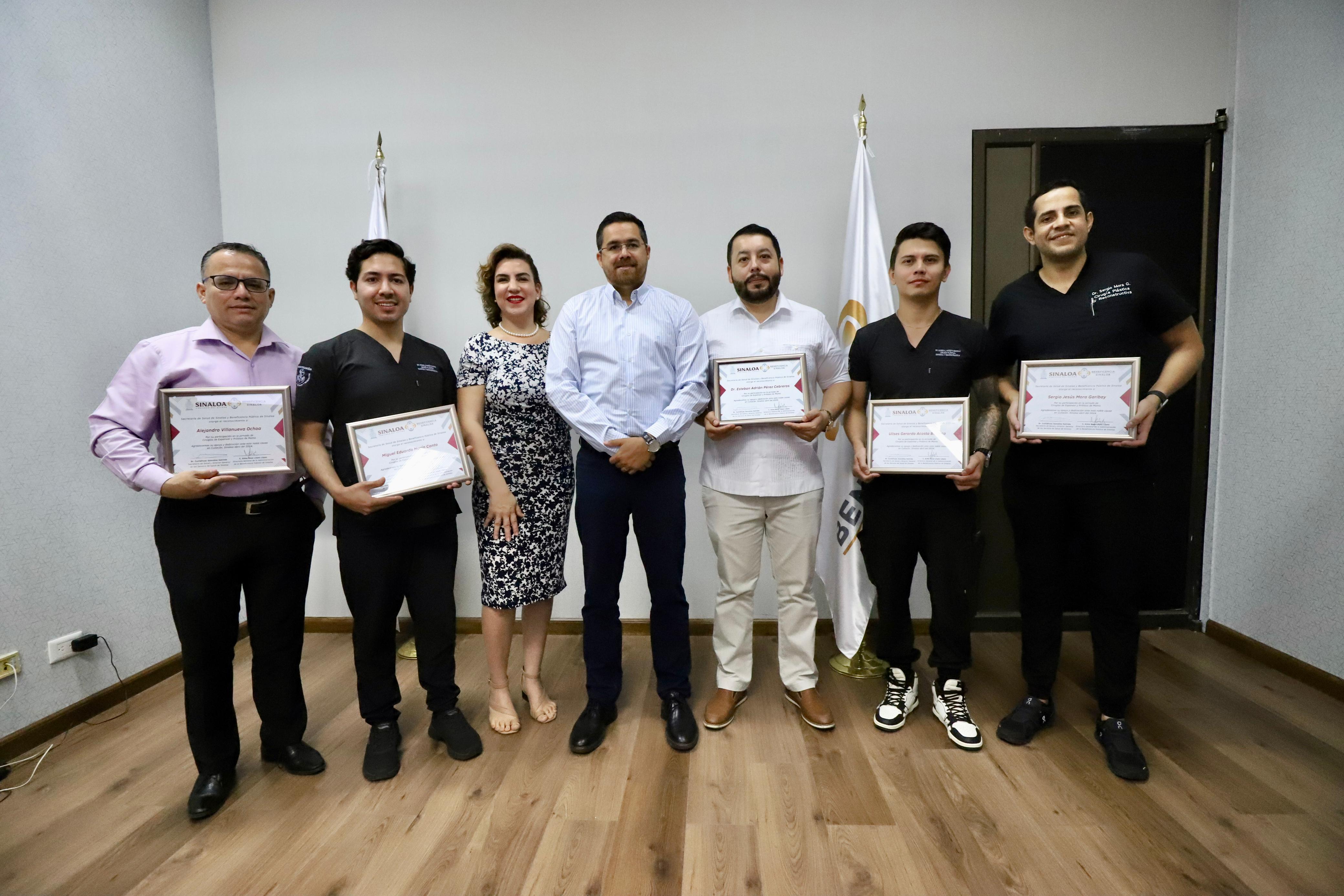 Médicos cirujanos sosteniendo sus reconocimientos junto al secretario de Salud Cuitláhuac González