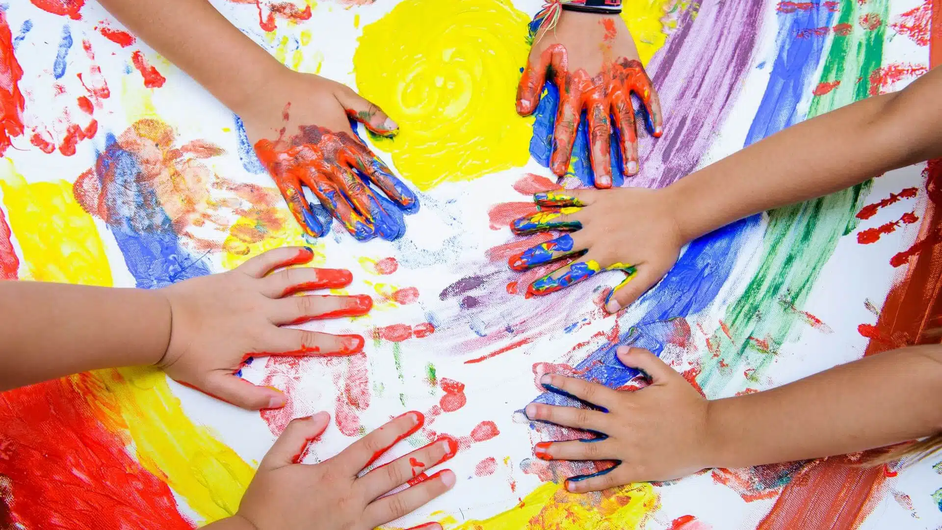 Manos de niños con pintura realizando una actividad recreativa