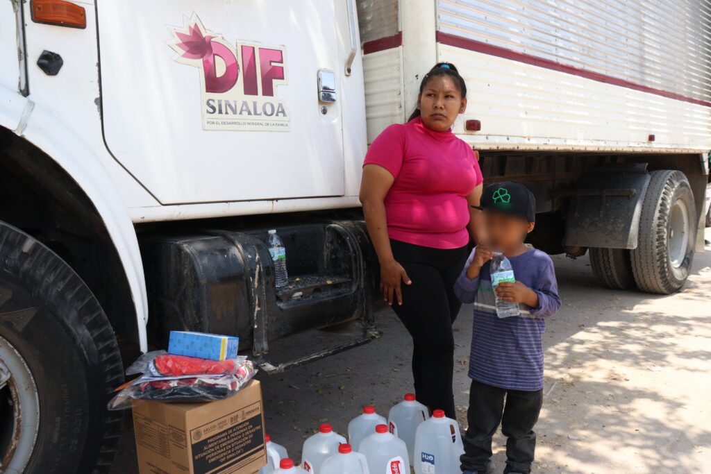 Mujer y niño reciben agua donada de Sistema DIF