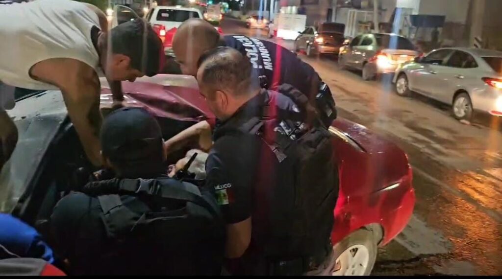 Policía Municipal y ciudadanos intentando sacar a don Heriberto de su vehículo