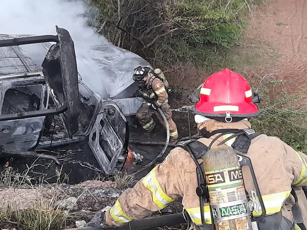 Bomberos Veteranos combatiendo las llamas derivadas del accidente vial