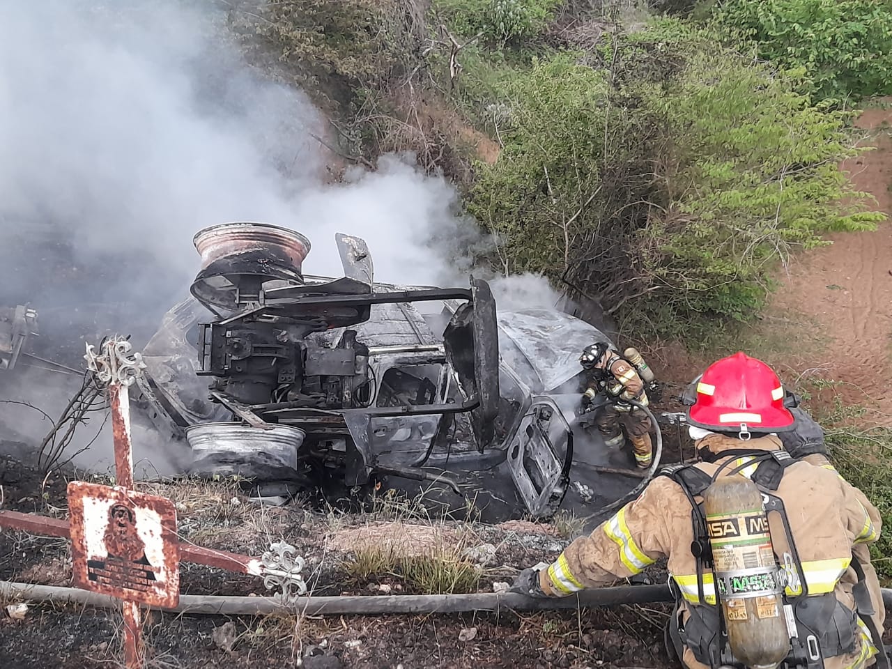 Bomberos combatiendo el incendio ocasionado por el accidente