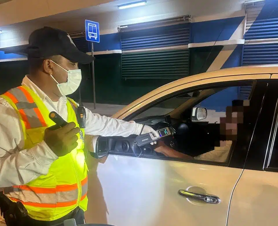Oficial realizando examen de alcoholímetro a un conductor