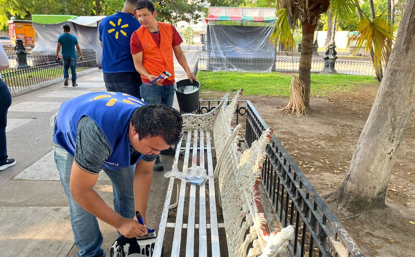 Voluntarios de fundación Walmart pintan una banca en la plazuela 27 de Septiembre de Los Mochis