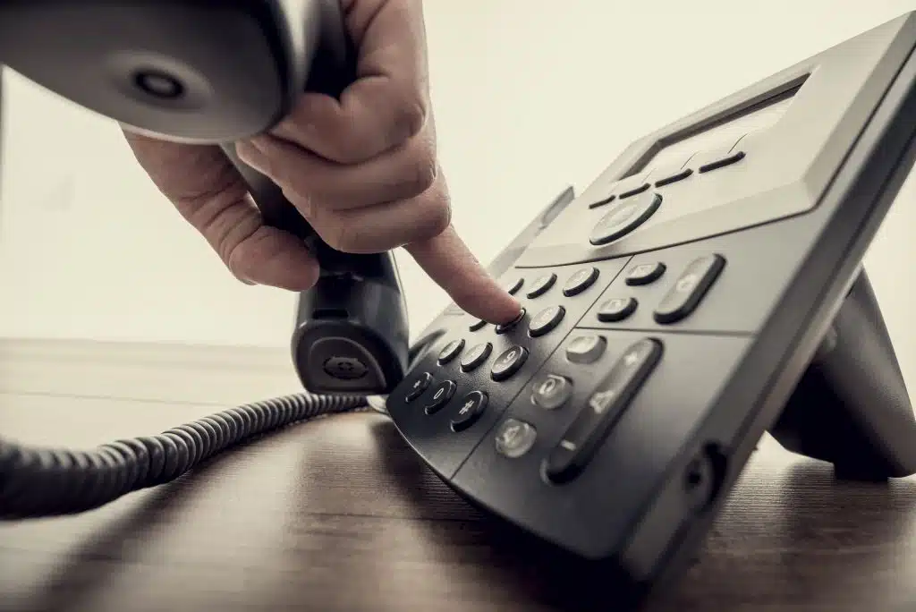 Una mano sosteniendo un teléfono mientras presiona una tecla del mismo con su dedo