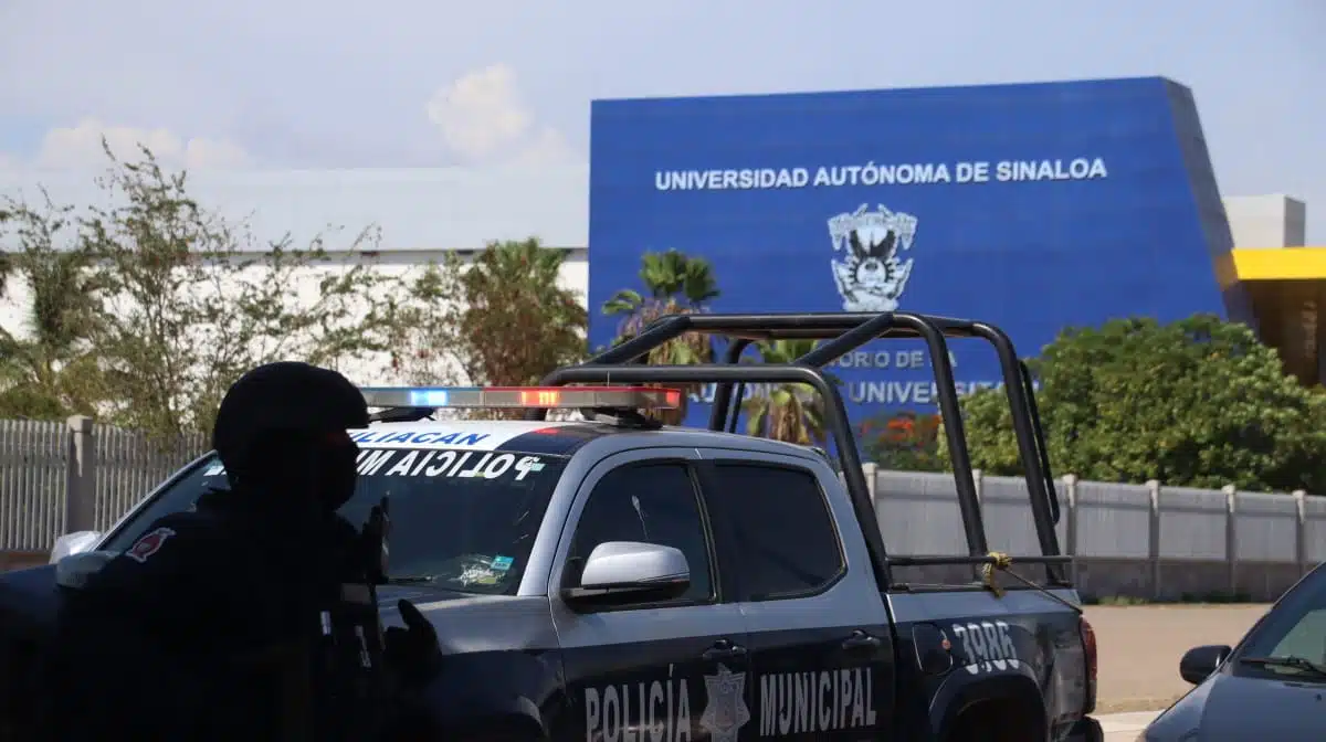 Patrulla y elemento de la Policía Municipal de Culiacán afuera de rectoría de la UAS