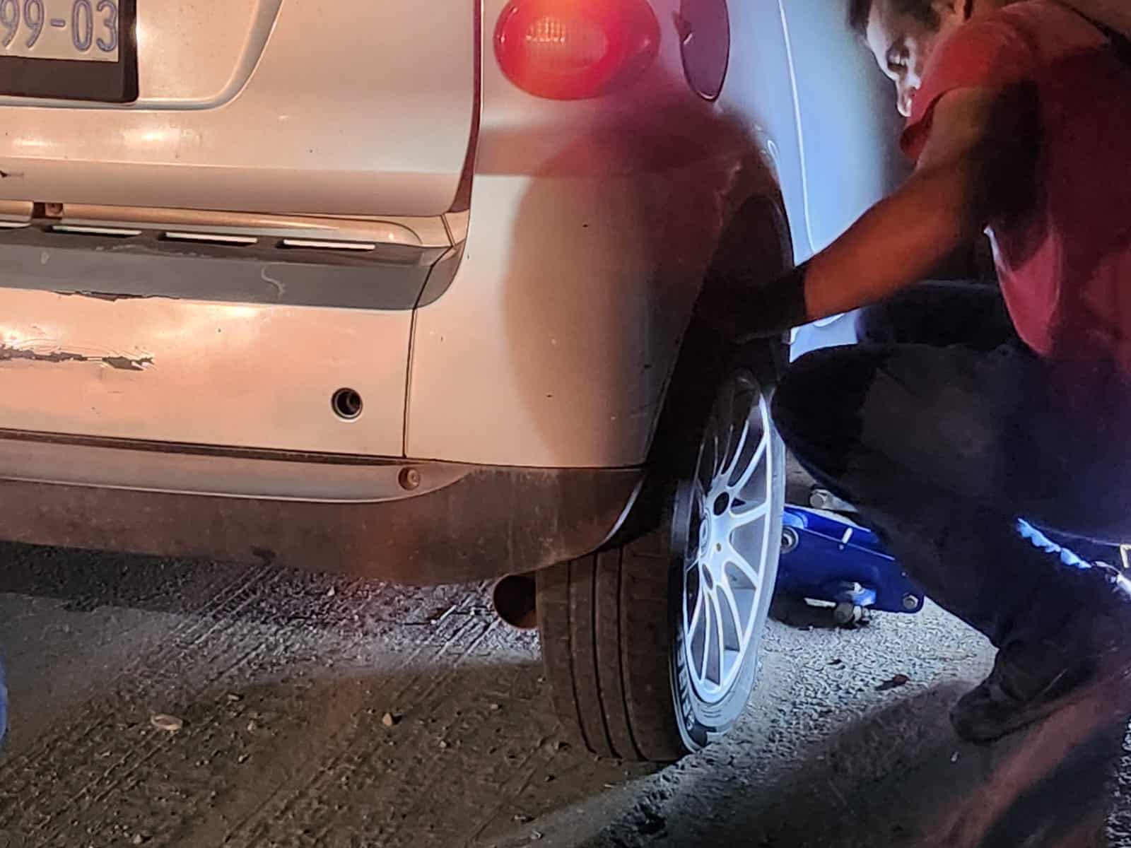 Persona utilizando un gato hidráulico luego de que su vehículo terminó ponchado
