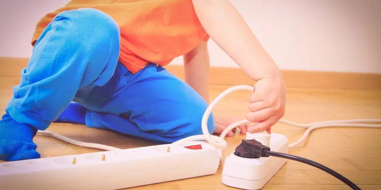 Niño conectando un enchufe en una extensión eléctrica
