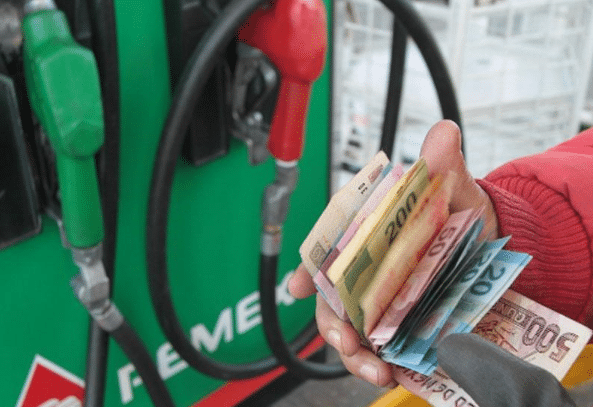 Persona con dinero en mano en una estación de gasolina.