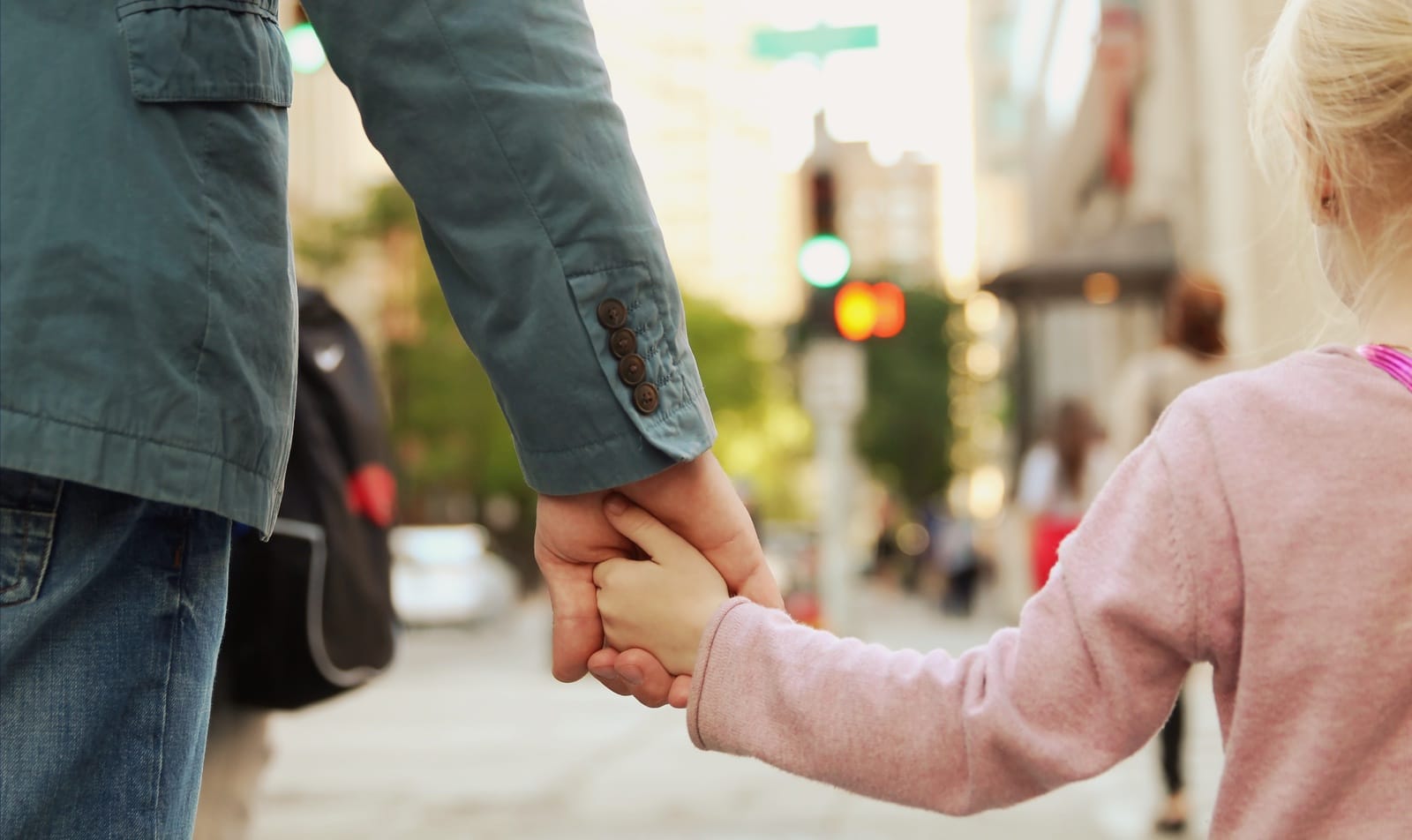 Padre de familia llevando a su hija de la mano por la ciudad