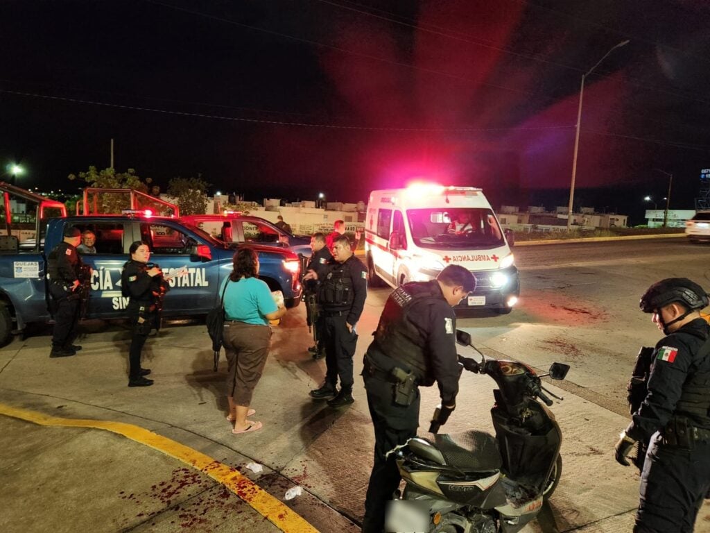 Policía Estatal asegurando la motocicleta del agresor. Al fondo hay una ambulancia de la Cruz Roja que llegó para atender al hombre agredido.