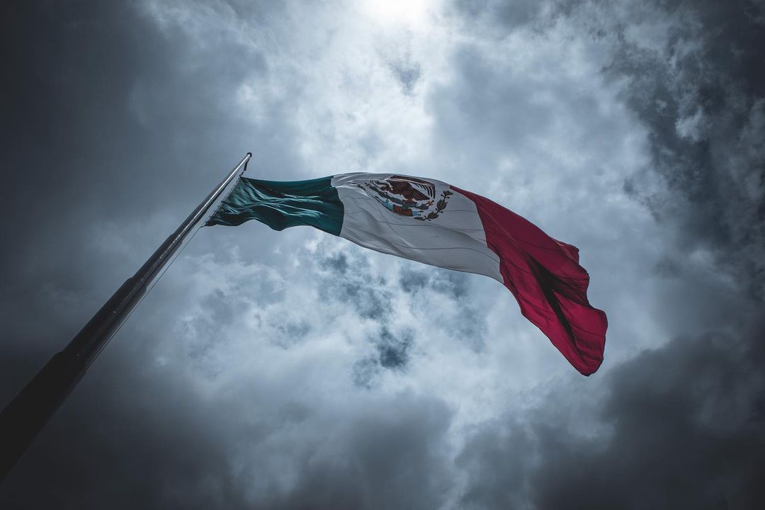 Bandera de México bajo un cielo cerrado y nuboso